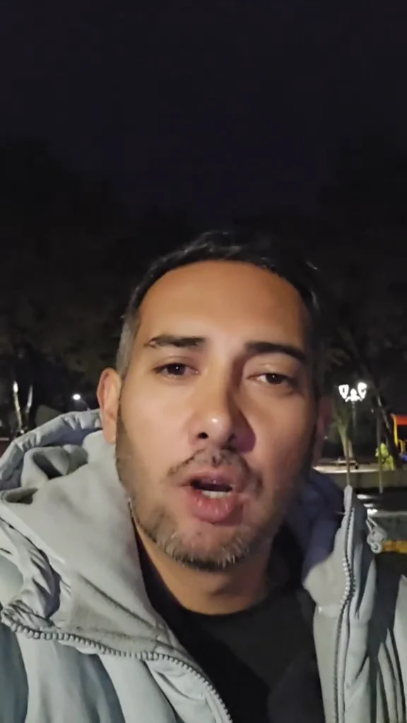 Daniel hablando a cámara de noche, al aire libre, con luces de fondo.